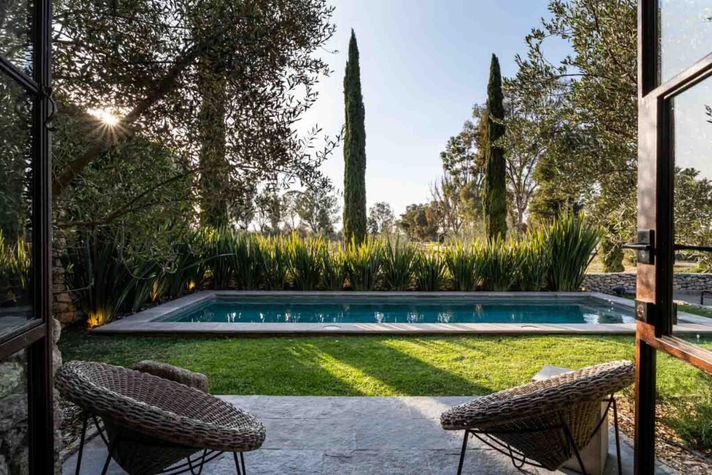 Alberca rectangular rodeada de ciprés y jardín tipo resort en desarrollo de comunidad cerrada, San Miguel de Allende