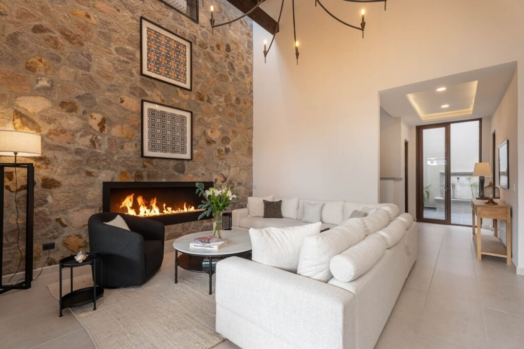 Sala contemporánea con muro de piedra natural y chimenea lineal en propiedad del barrio Balcones, San Miguel de Allende