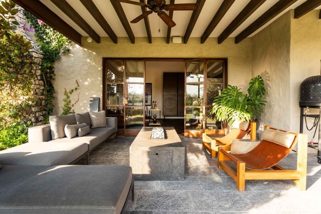 Terraza cubierta con mobiliario de diseño contemporáneo y vista al jardín en desarrollo de comunidad cerrada, San Miguel de Allende