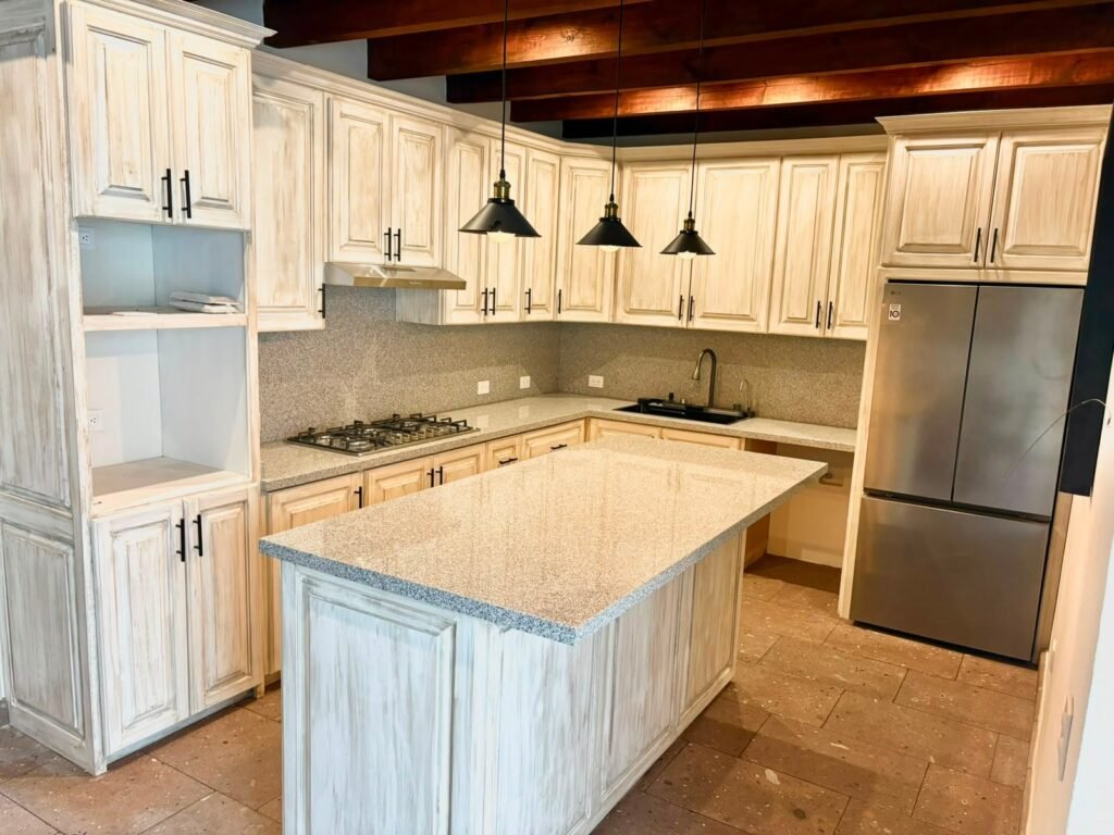 Cocina rústica con gabinetes de madera y isla central de granito en propiedad del barrio San Antonio, San Miguel de Allende