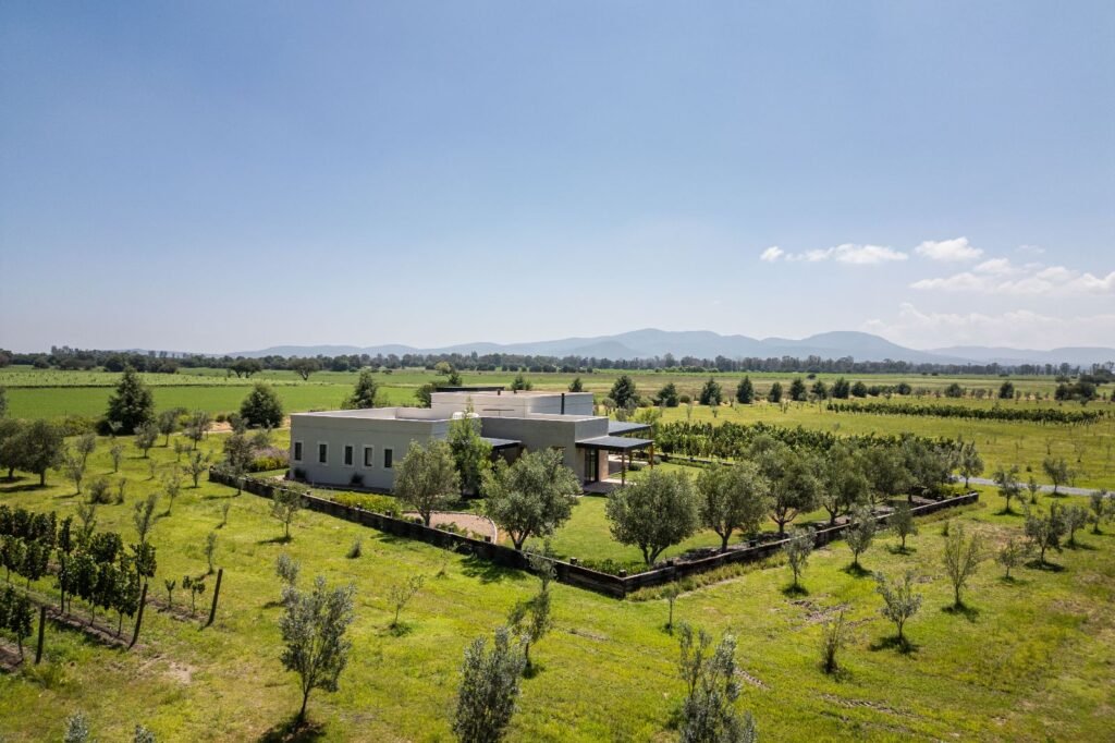 Vista panorámica aérea de residencia moderna rodeada de campo abierto y árboles frutales en desarrollo de comunidad cerrada, San Miguel de Allende