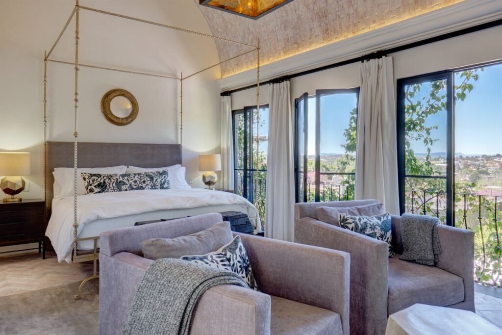Recámara con cama de dosel de herrería y vista panorámica a los cerros de San Miguel de Allende desde propiedad del Centro Histórico