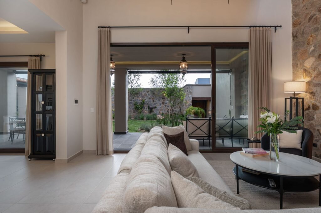 Sala amplia con muro de piedra, ventanales y vista al jardín en propiedad del barrio Balcones, San Miguel de Allende