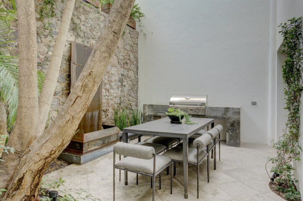 Patio interior con árbol natural integrado, asador y comedor exterior en propiedad colonial del Centro Histórico, San Miguel de Allende
