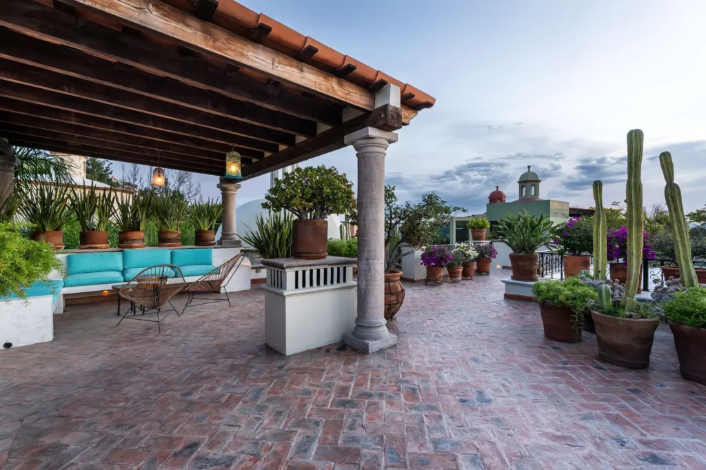 Terraza en azotea con pergola de madera, cactus en macetas y vista a cúpula colonial en propiedad de Guadiana, San Miguel de Allende
